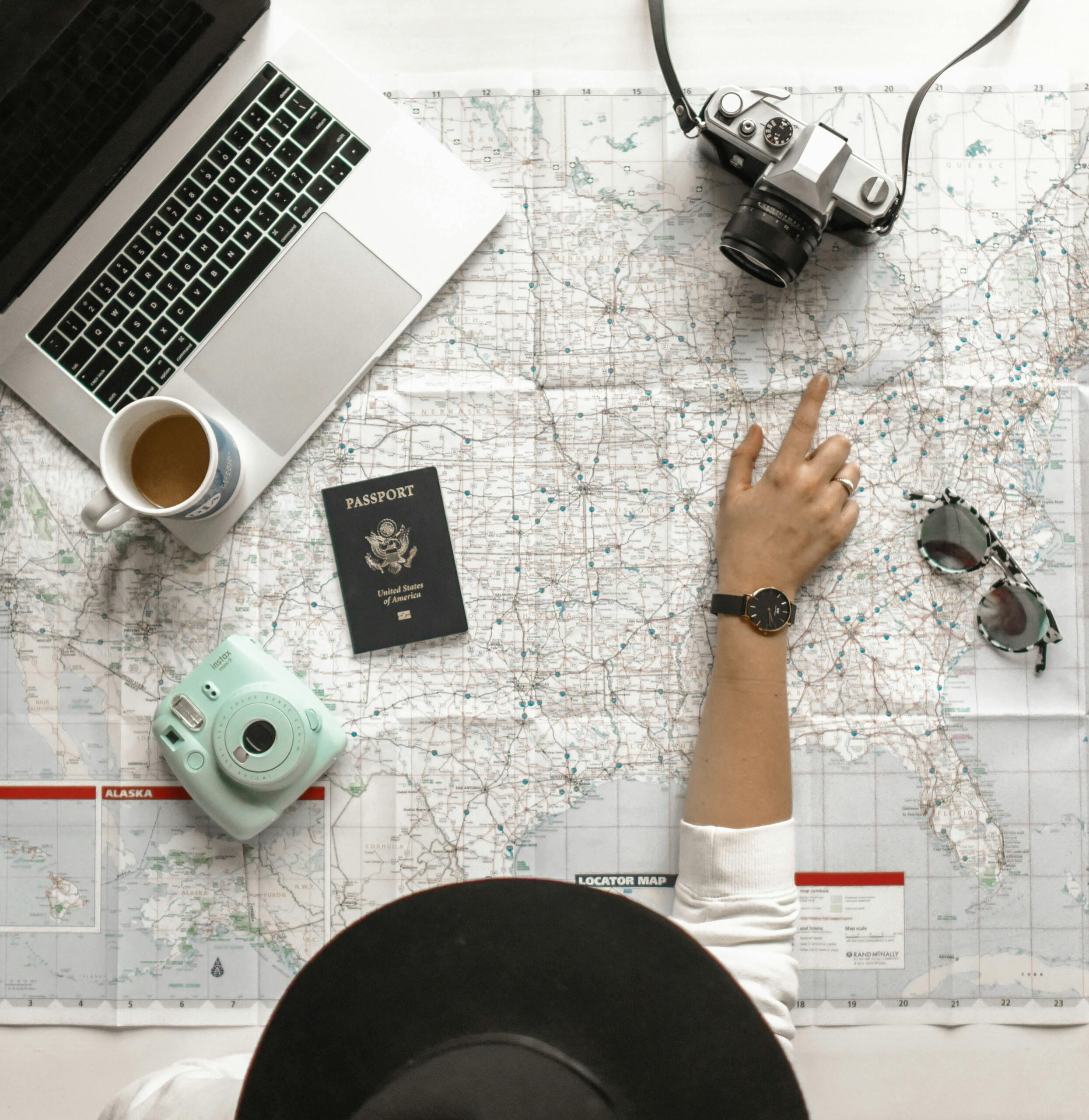 Travel map with passport, sunglasses, camera, and laptop.